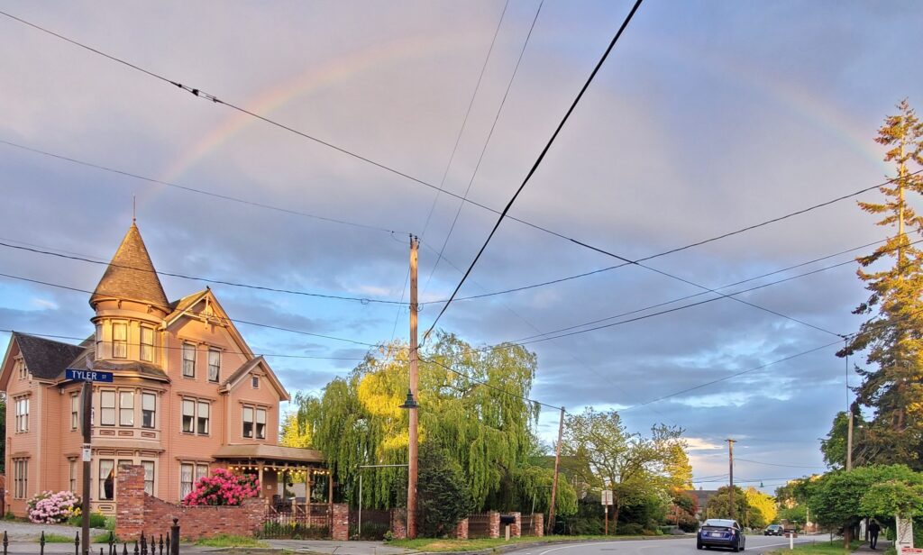The Adams Pragge House, an 1889 Victorian home in Port Townsend, Washington, viewed from the corner of Tyler Street and F Street beneath a rainbow.