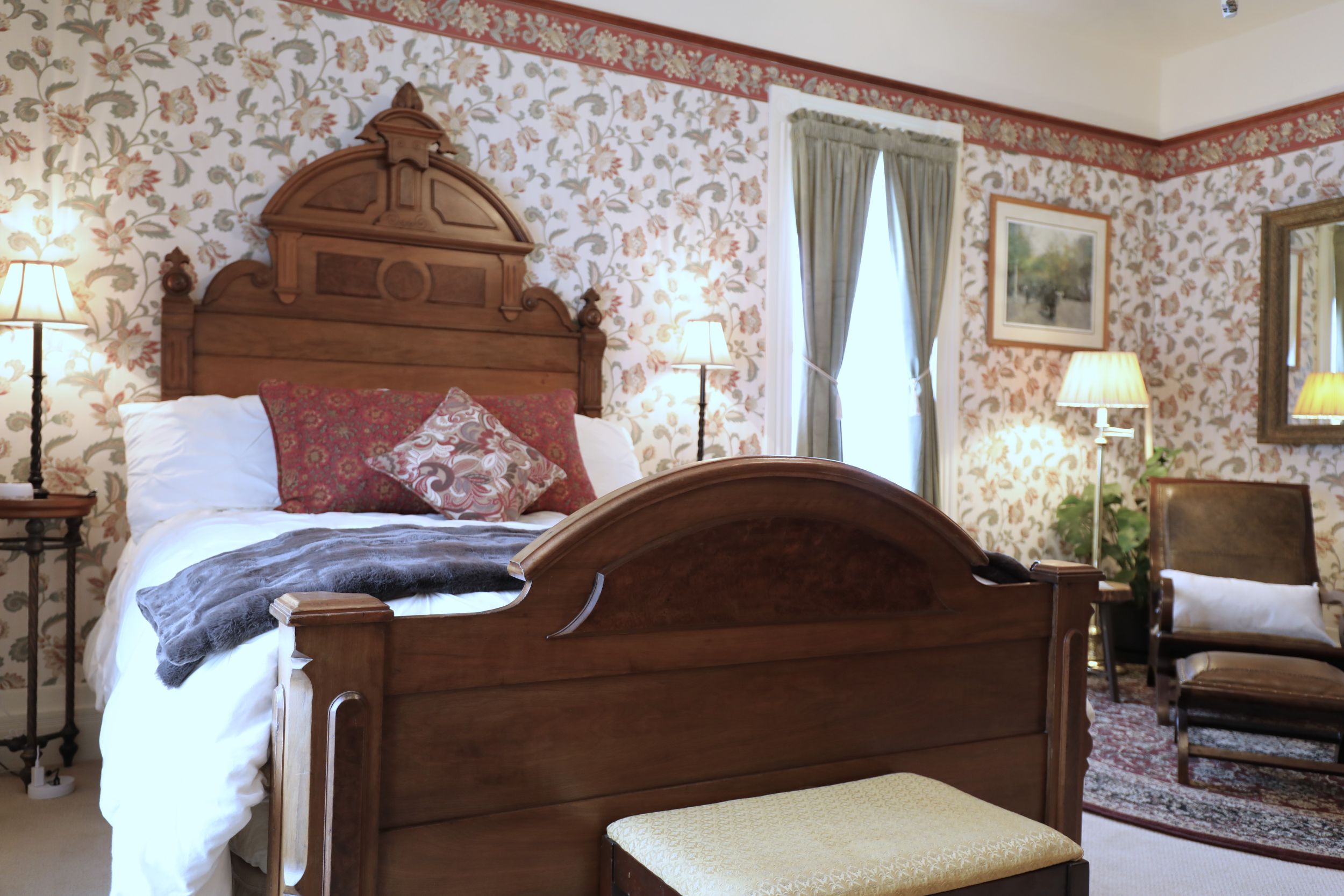 Renaissance Revival burled walnut bed in the Cascadia Suite at The Adams Pragge House, with floral wallpaper and seating area beyond