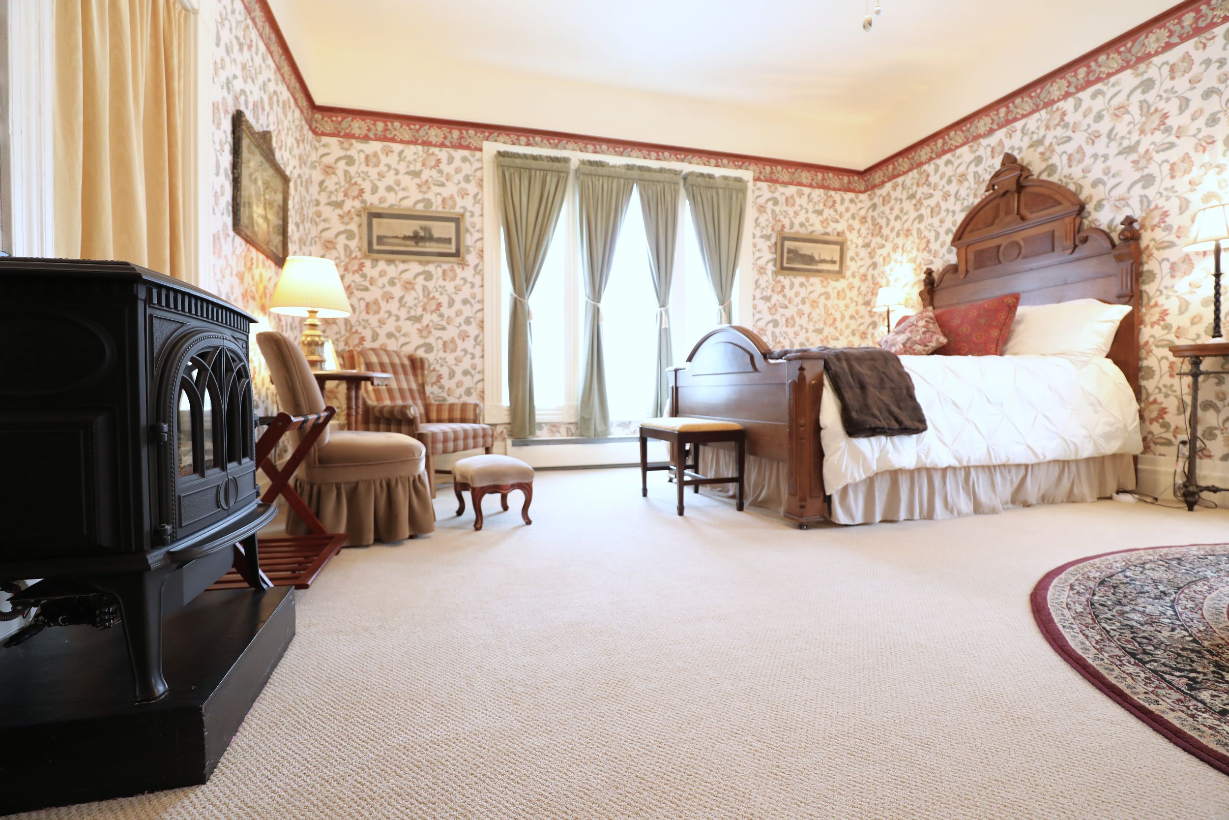 Full room view of the Cascadia Suite at The Adams Pragge House showing propane fireplace, seating area, and Renaissance Revival walnut bed