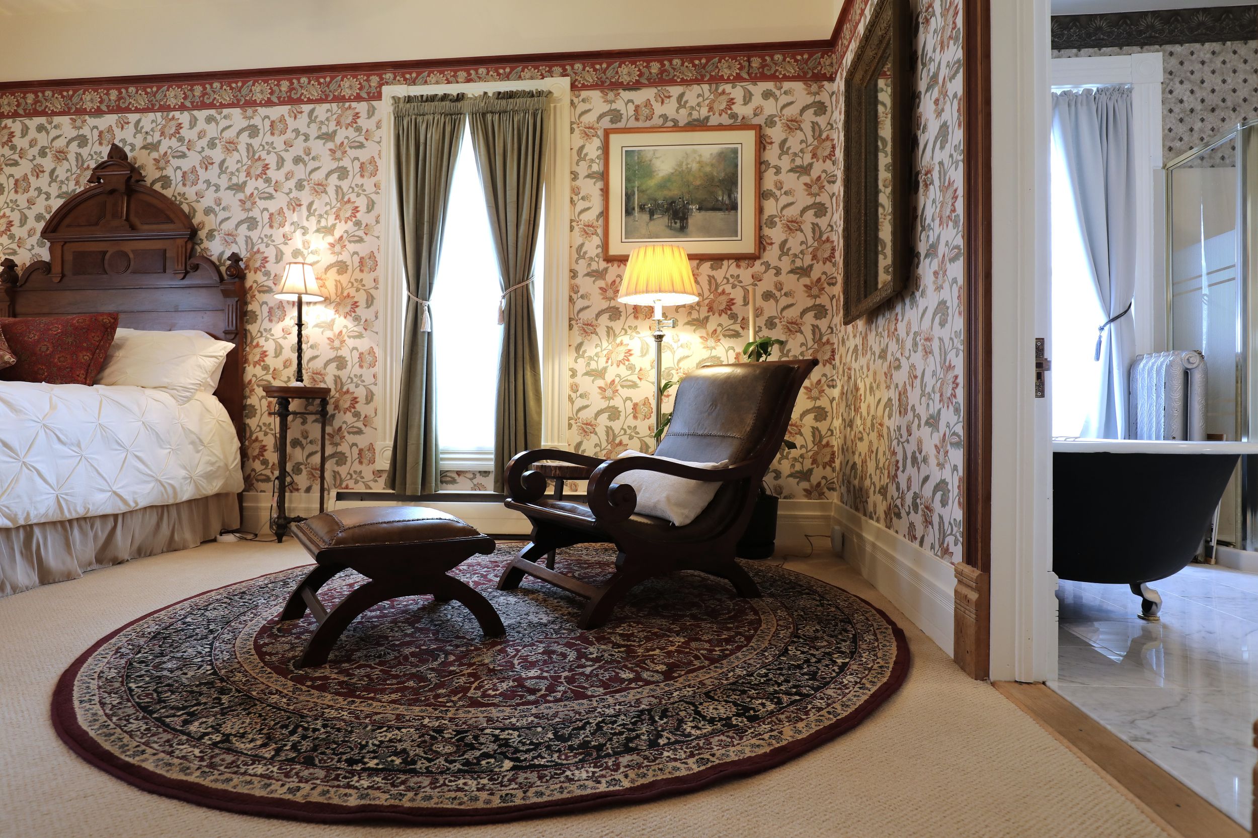Plantation-style reclining chair and ottoman in the Cascadia Suite at The Adams Pragge House, with clawfoot tub visible through the bathroom doorway
