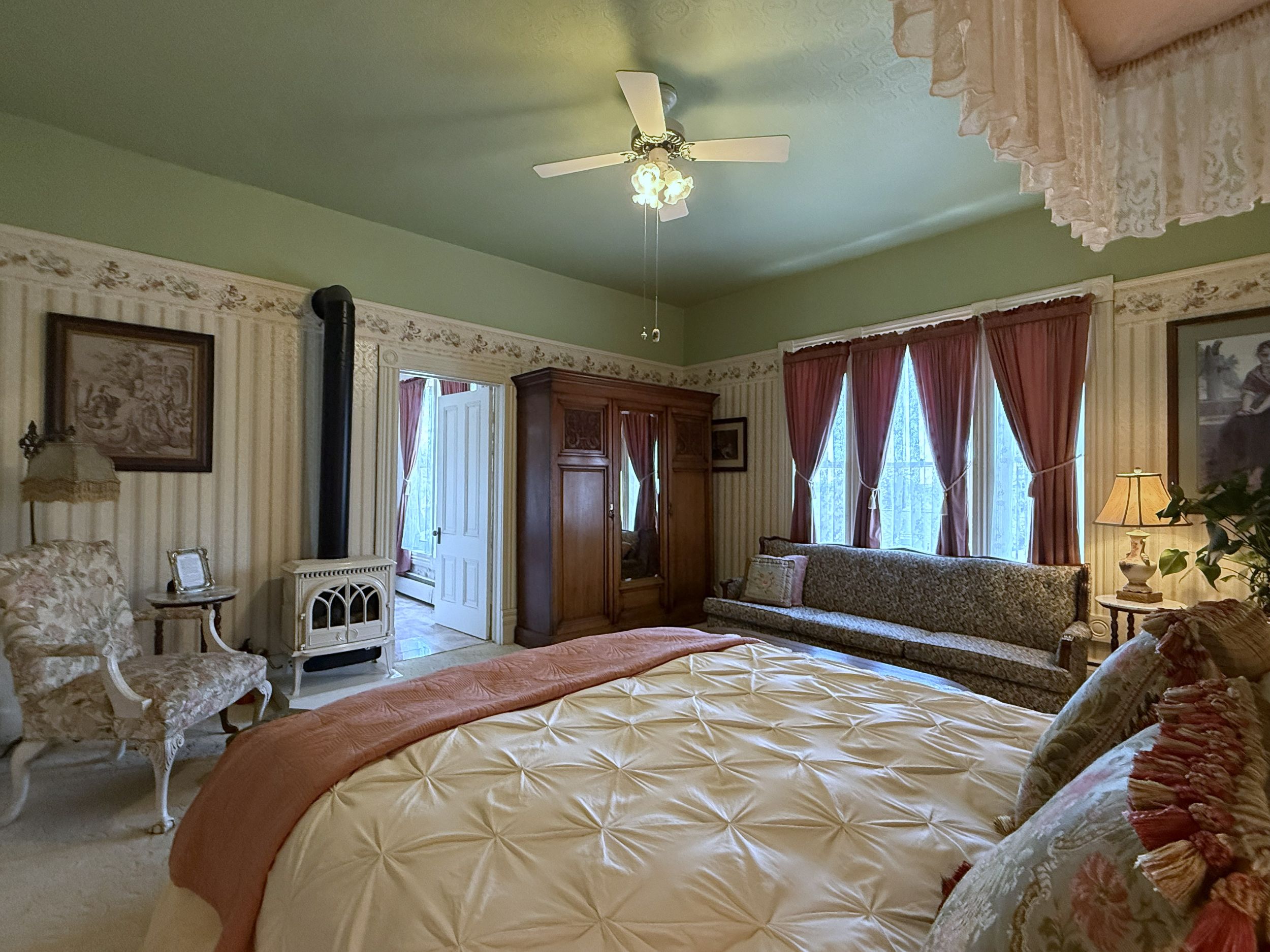 Victoria Suite at The Adams Pragge House showing antique armoire, sofa seating area, propane fireplace, and east-facing windows