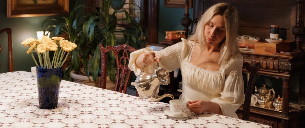 A woman pours tea from a silver teapot in a Victorian Dining Room